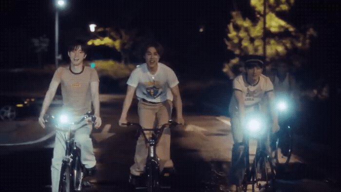 a group of people riding bikes down a street at night