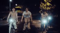 a group of people riding bikes down a street at night