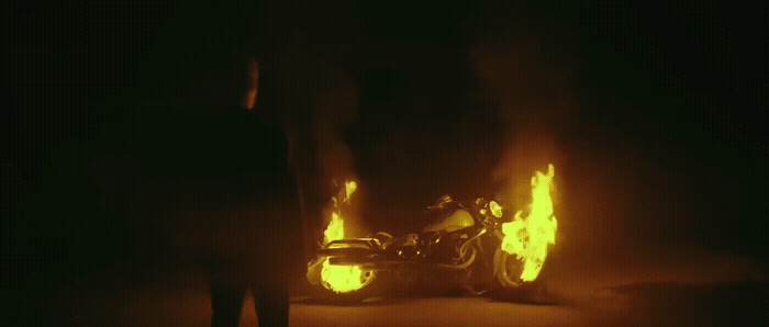 a person standing next to a motorcycle on fire