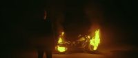 a person standing next to a motorcycle on fire
