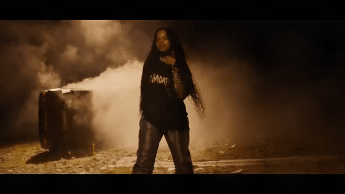 a man with long hair standing in front of smoke