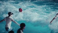 a group of people in the water playing with a frisbee
