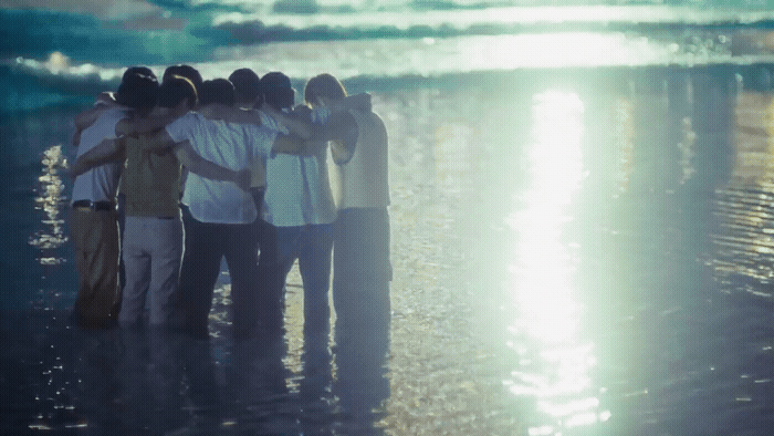 a group of people standing on top of a beach next to the ocean