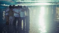 a group of people standing on top of a beach next to the ocean