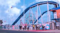 a group of people standing in front of a roller coaster