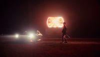 a man walking next to a car at night