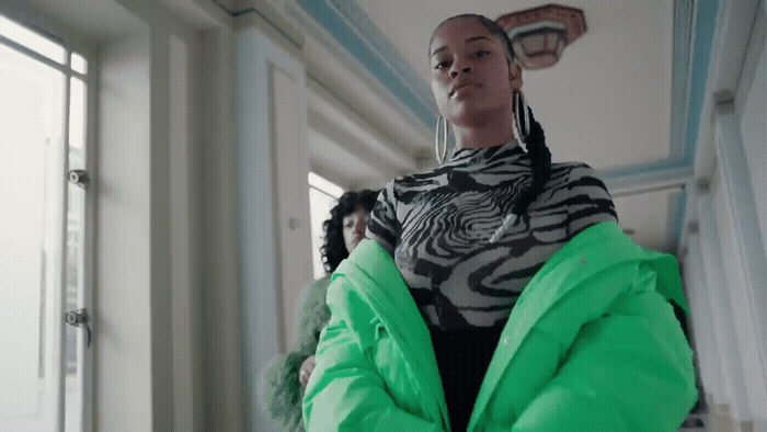 a woman in a green jacket standing in a room