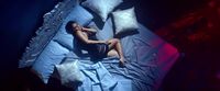 a woman laying on a bed with blue sheets and pillows