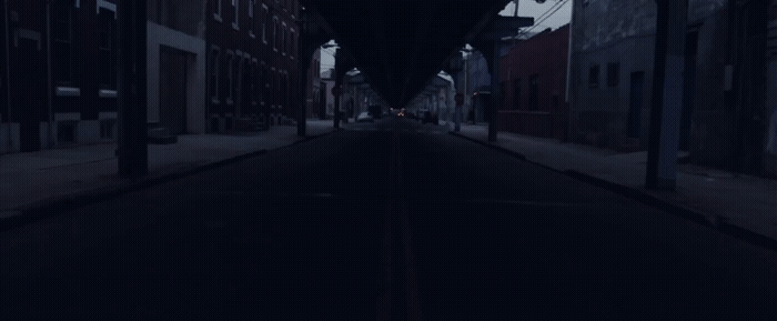 a dark street with a clock on the side of it