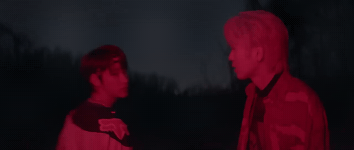 two men standing next to each other in the dark