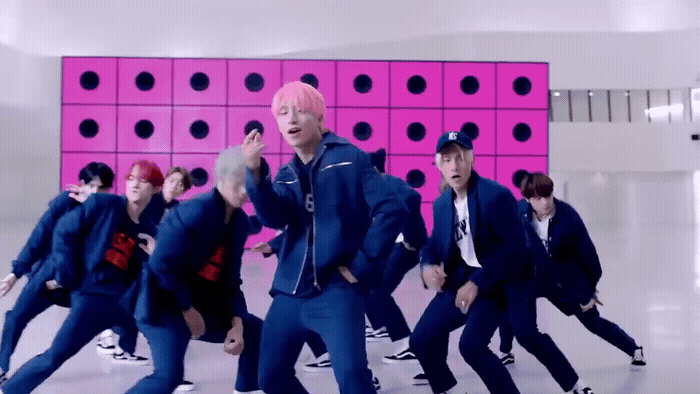 a group of young men dancing in front of a pink wall