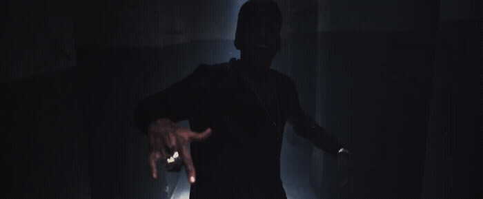 a man standing in a dark room with his arms out