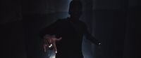 a man standing in a dark room with his arms out