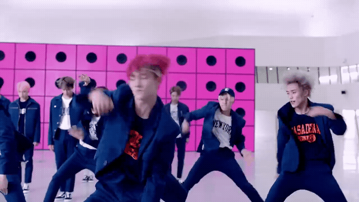 a group of young men dancing in front of a pink wall