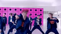 a group of young men dancing in front of a pink wall