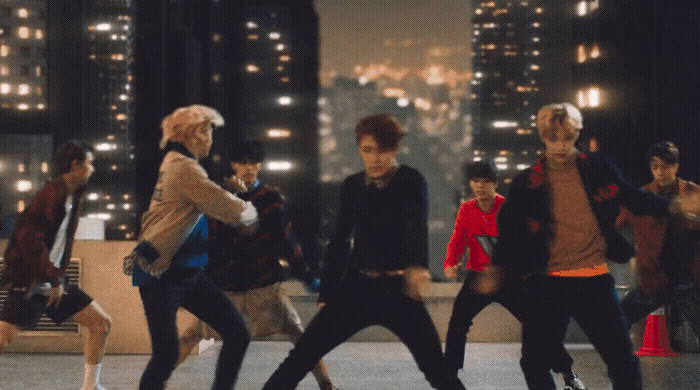 a group of young men dancing in a city at night