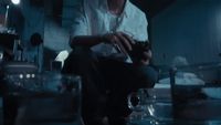 a man sitting in a kitchen next to a glass of water