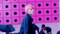a man with pink hair walking on a runway