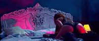 two people sitting on a bed in a dark room