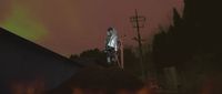 a man standing on top of a roof next to a fire