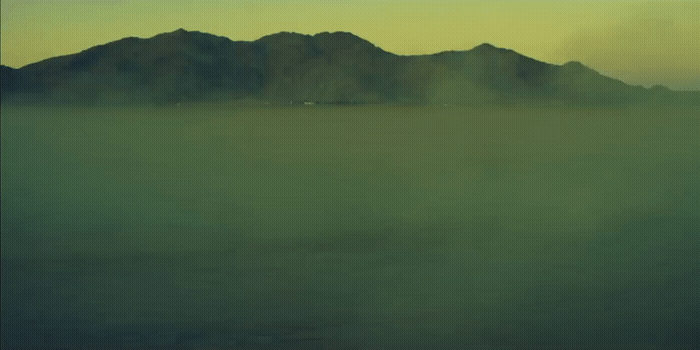a foggy landscape with mountains in the distance