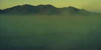 a foggy landscape with mountains in the distance