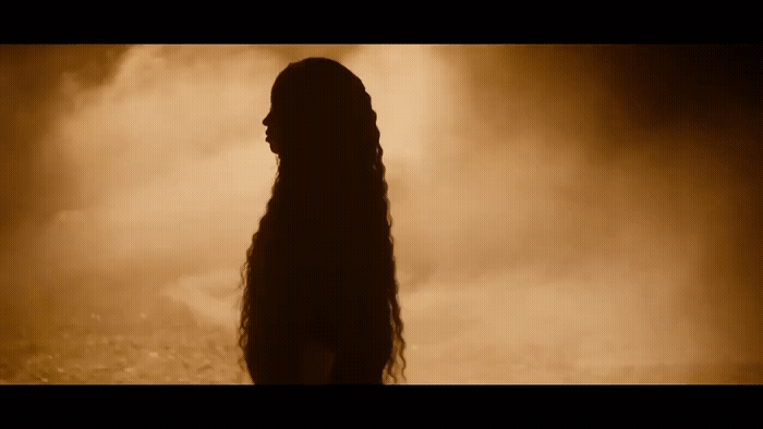 a woman with long hair standing in front of smoke