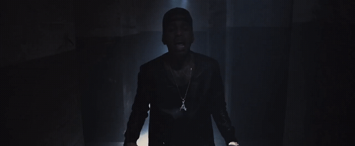 a man standing in a dark room with his hands in his pockets