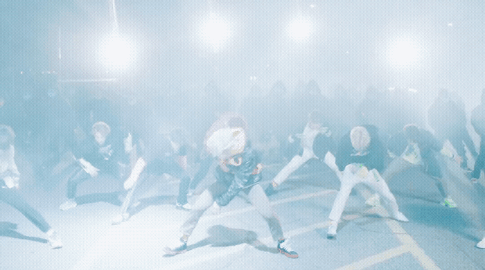 a group of people dancing in a foggy area