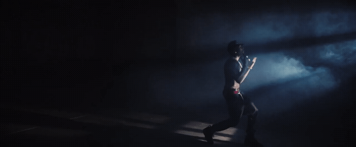a woman standing in the dark with her hands on her hips
