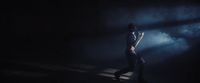 a woman standing in the dark with her hands on her hips