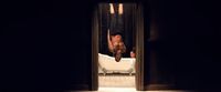 a man hanging upside down from a bed in a dark room