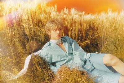 a young man sitting in a field of tall grass