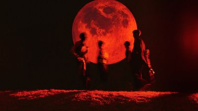 a group of people standing in front of a red moon