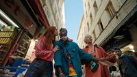 a group of people walking down a street next to tall buildings