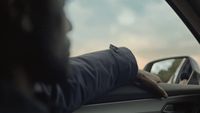 a man driving a car with his hand on the dashboard