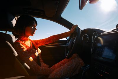 a woman sitting in a car with a steering wheel