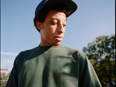 a young man wearing a green shirt and a black hat