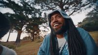 a man with long dreadlocks smiles at the camera