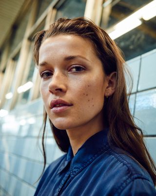 a woman with freckled hair standing in front of a wall