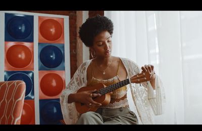 a woman sitting in a chair playing a guitar