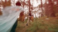 a blurry photo of two people running through a forest