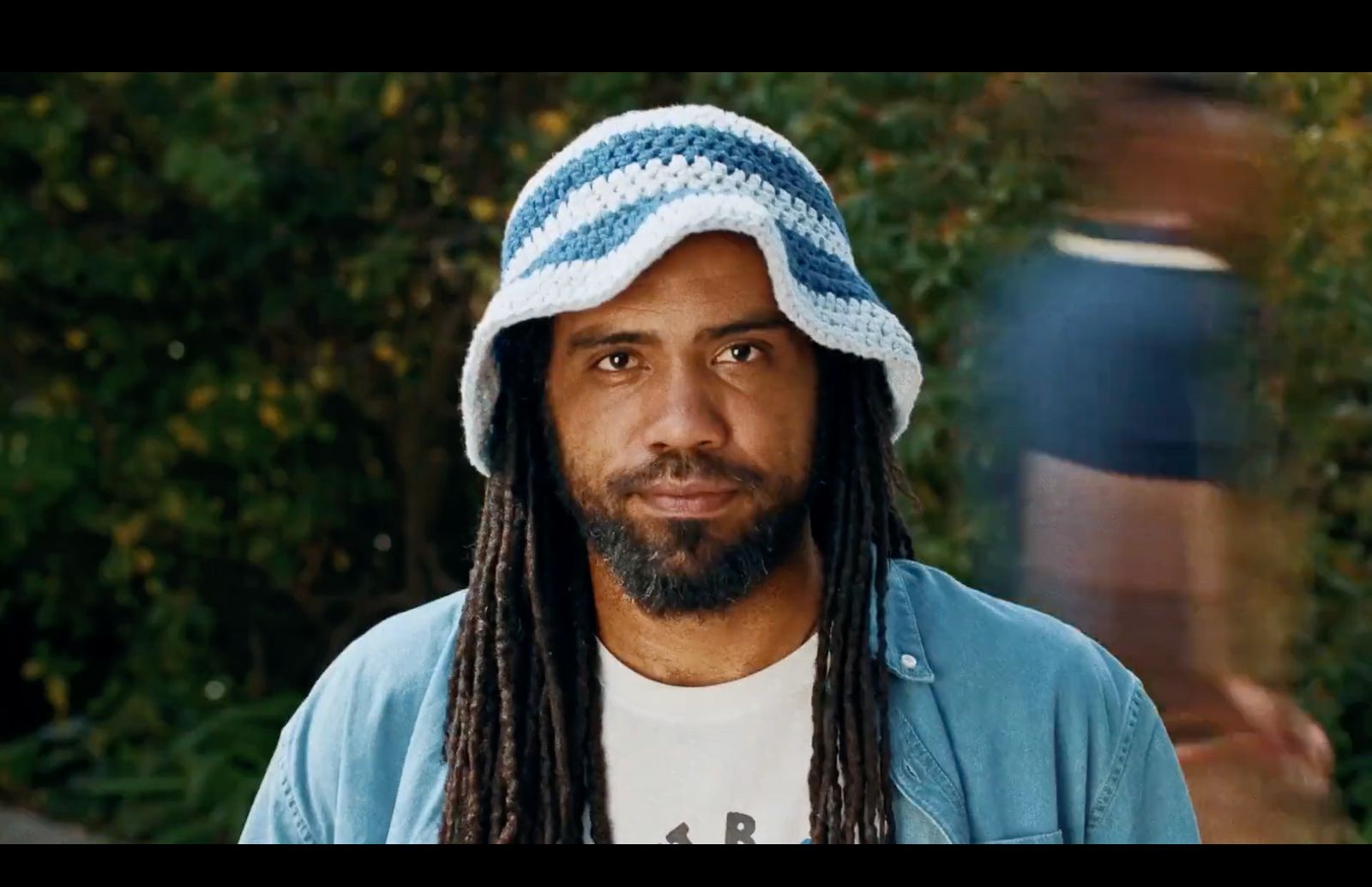 a man with dreadlocks wearing a blue and white hat