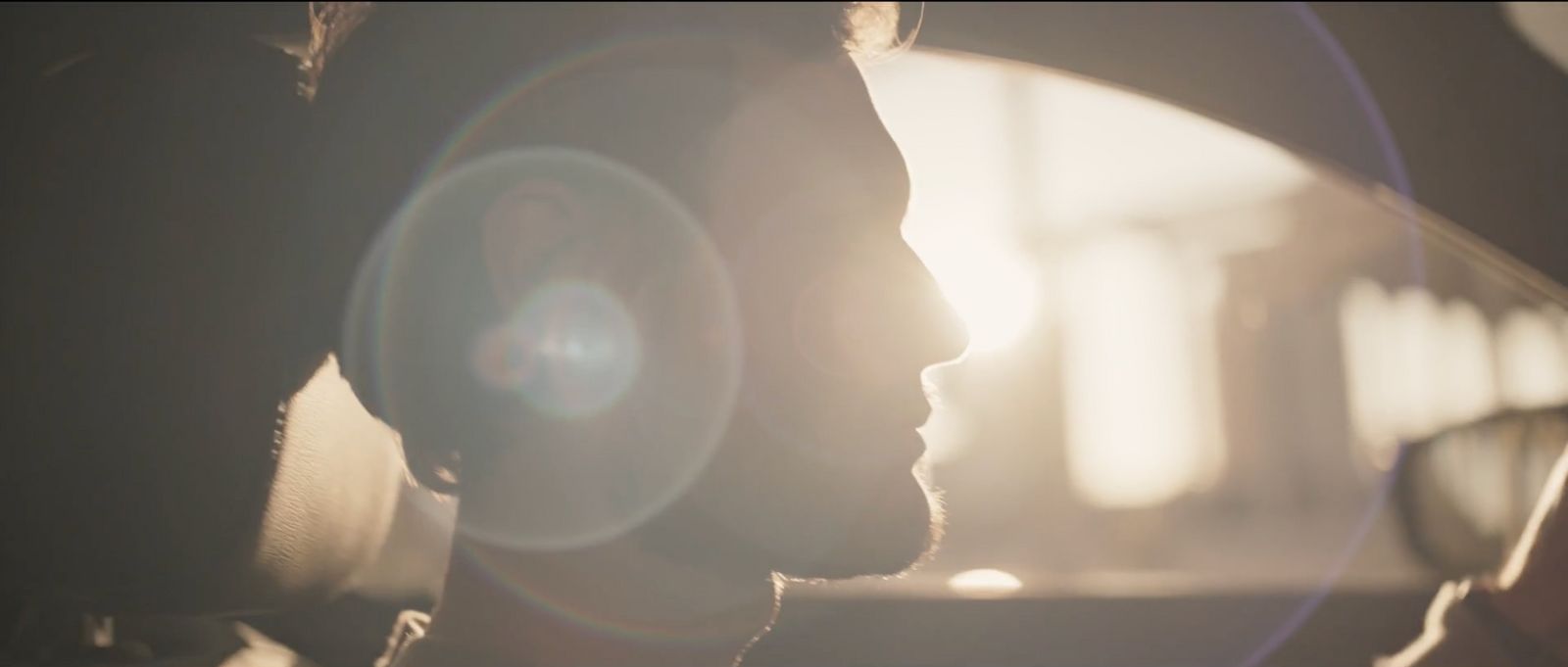 a man driving a car with the sun shining through the windshield