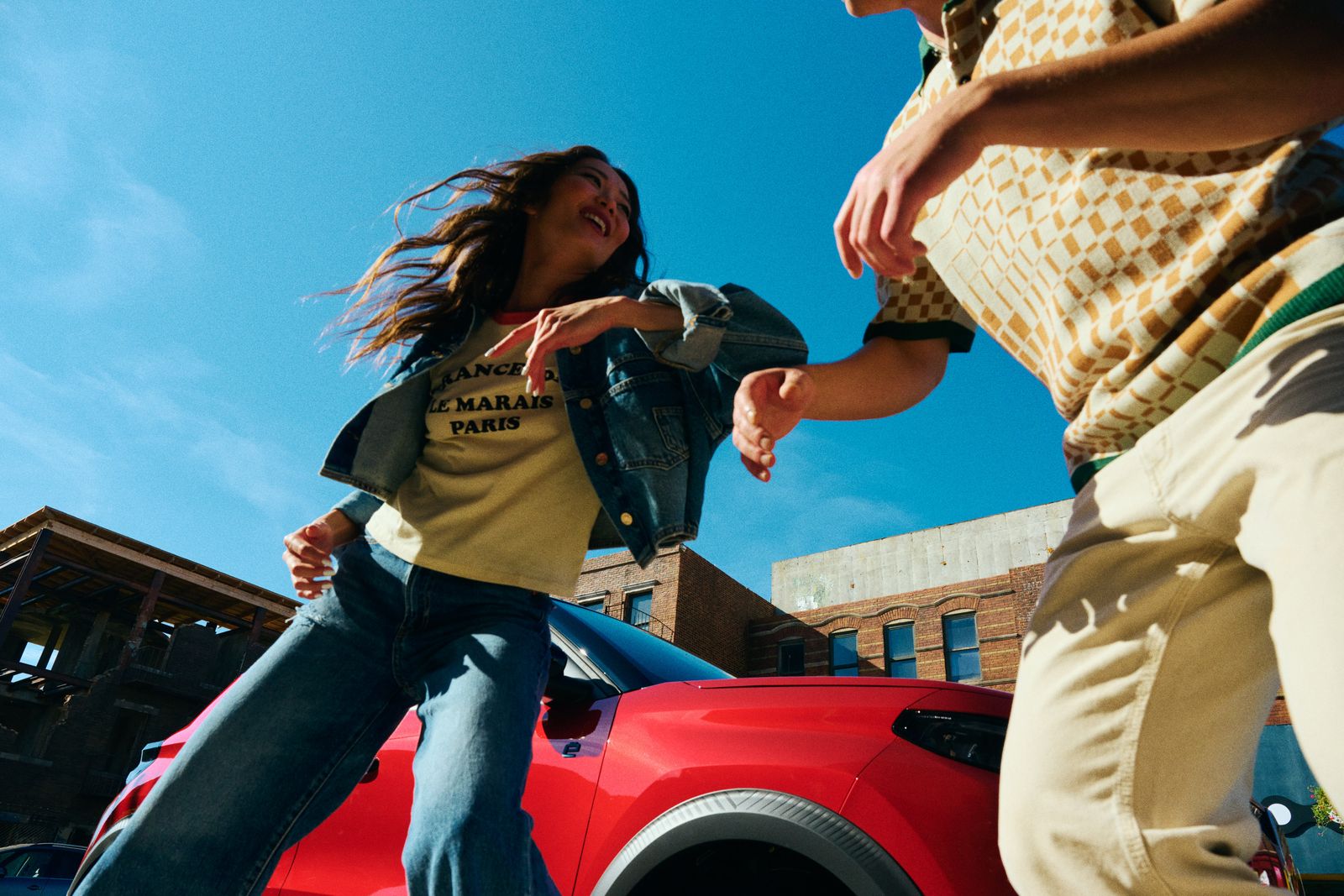 a man and a woman standing next to a red car