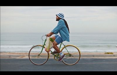 a man riding a bike down a street next to the ocean