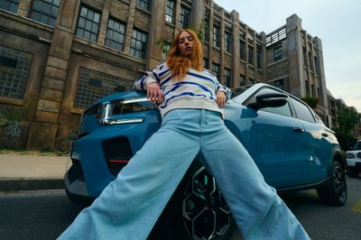 a woman leaning on a car in front of a building