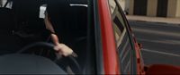 a woman driving a red car down a street