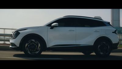 a white car driving down a street next to a bridge