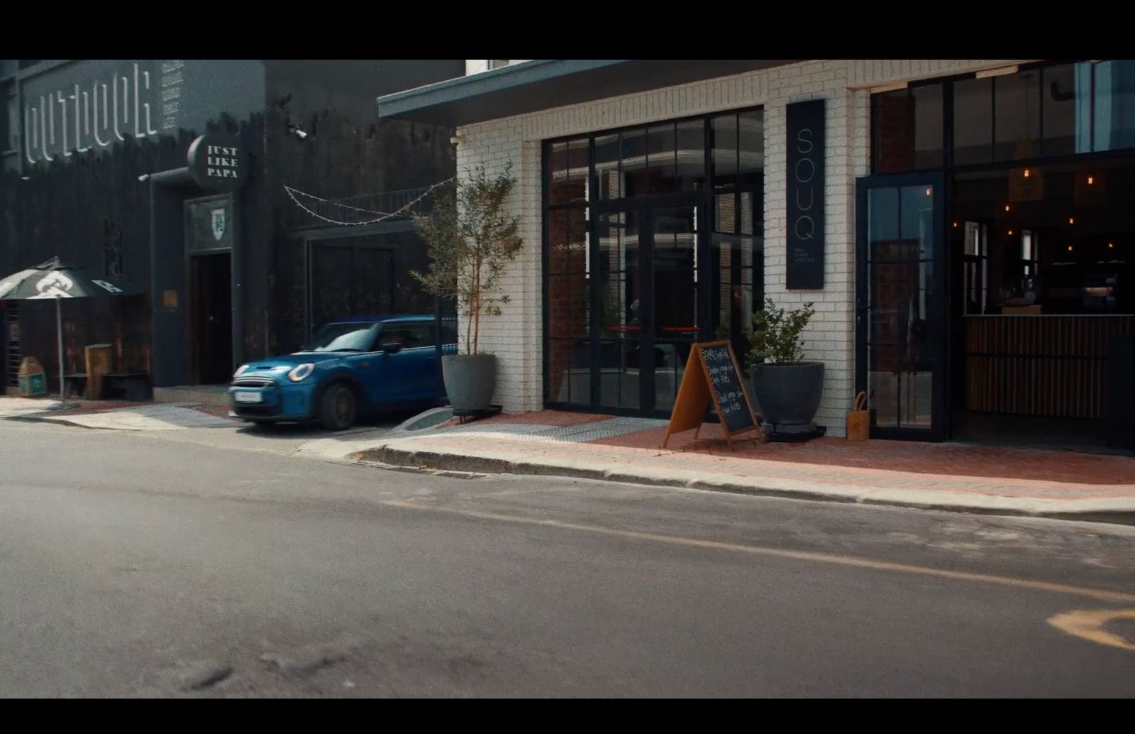 a blue car parked in front of a restaurant